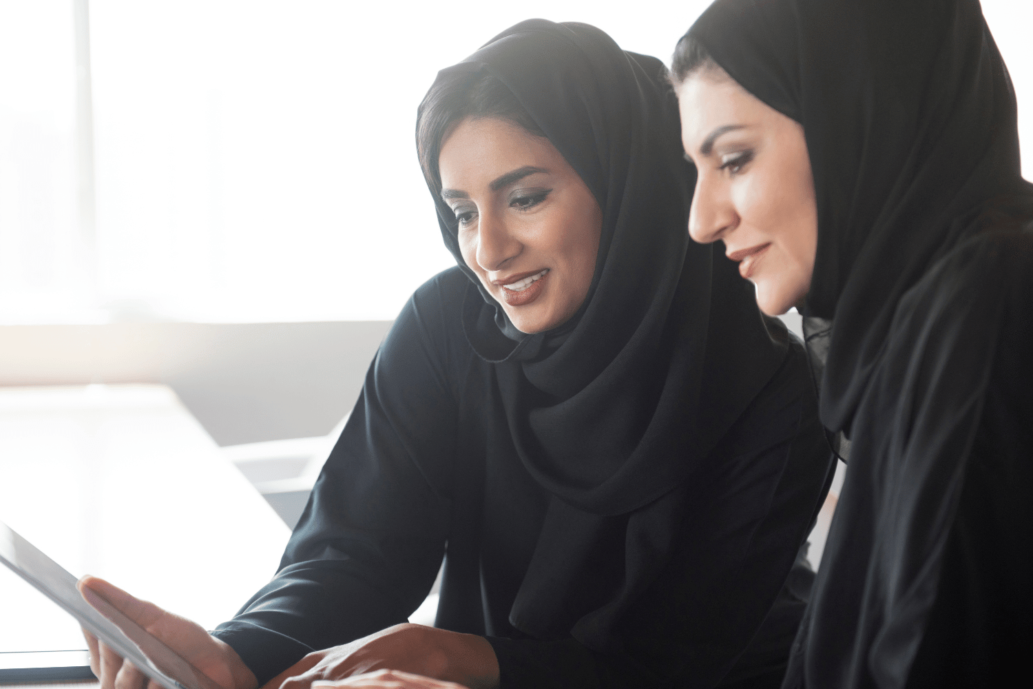 Saudi manager helping coach and mentor a fellow employee to help her onboard faster